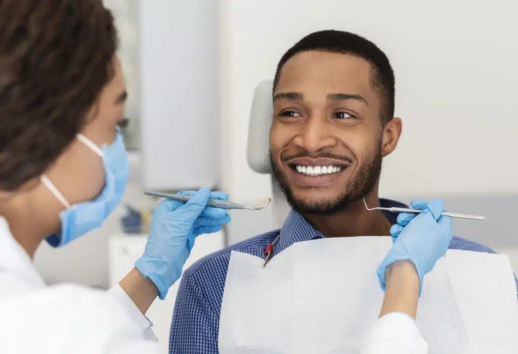 Smiling guy in dentist chair looking with trust at doctor